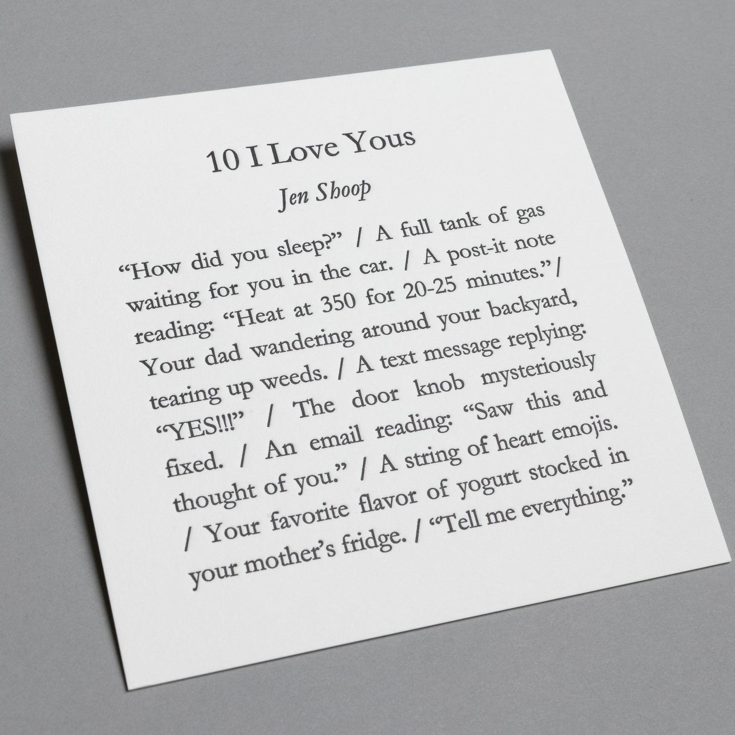 Angled view of “10 I Love Yous” 5×5 letterpress print, showing white paper and impressed black type.