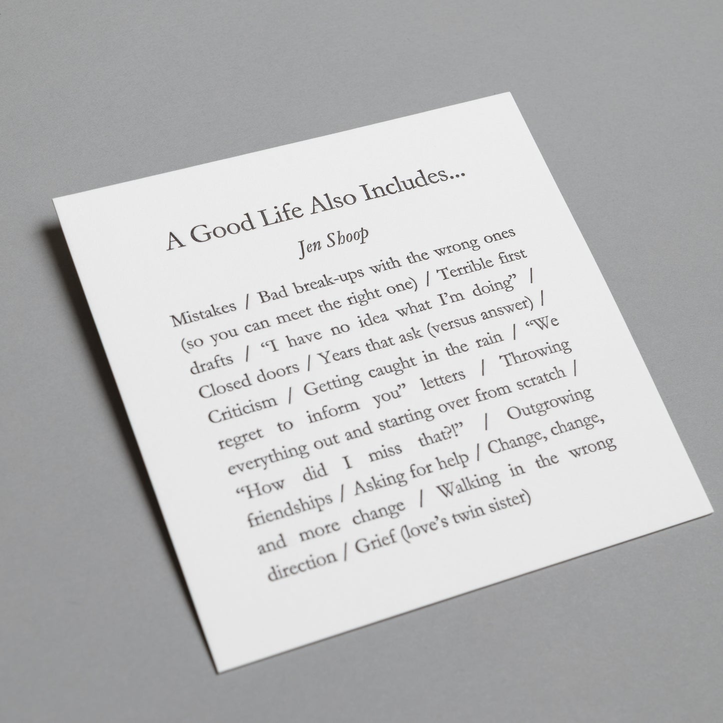 Angled view of “A Good Life Also Includes…” 5×5 letterpress print with impressed black type.