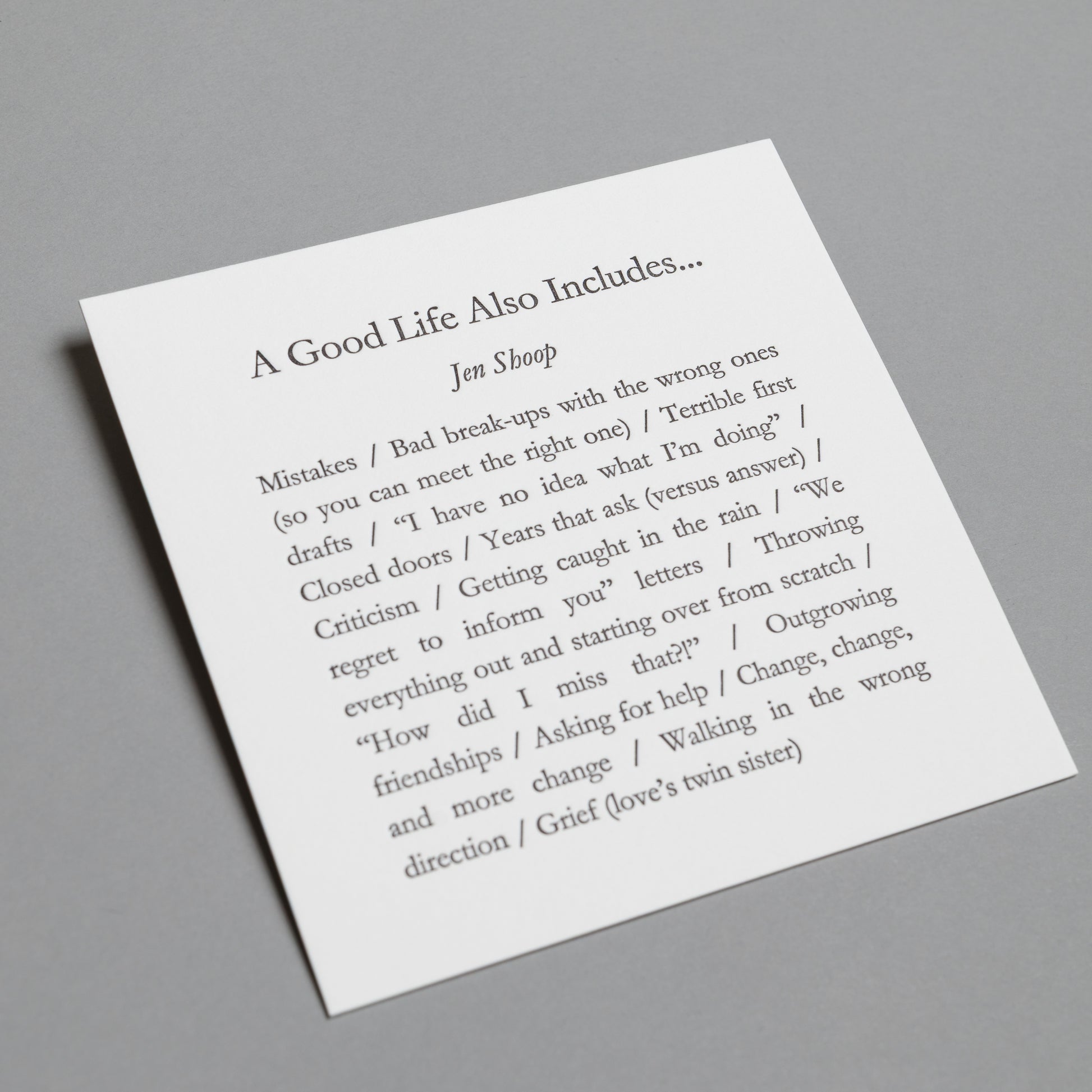 Angled view of “A Good Life Also Includes…” 5×5 letterpress print with impressed black type.