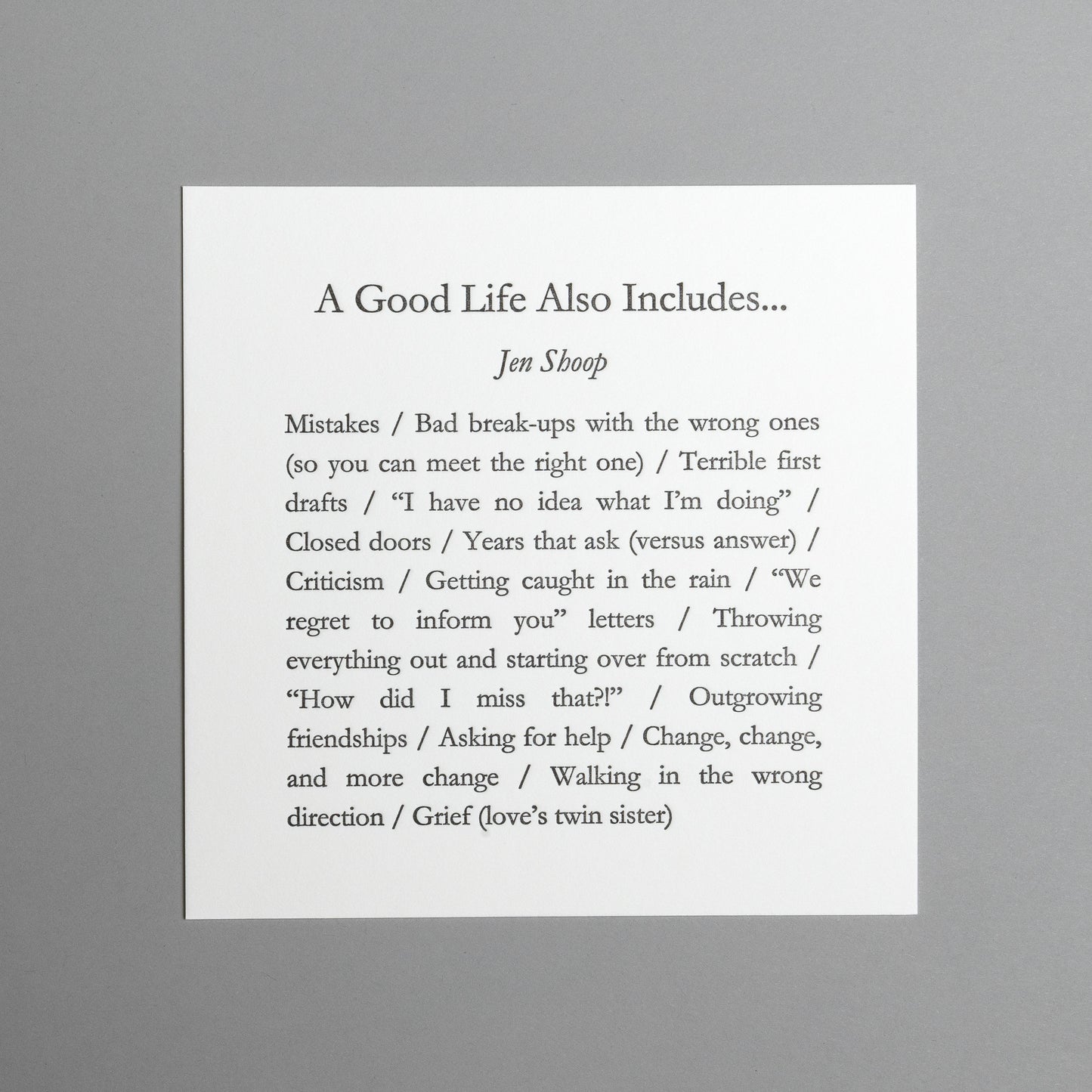 Front view of “A Good Life Also Includes…” 5×5 black letterpress print by Jen Shoop on white paper.