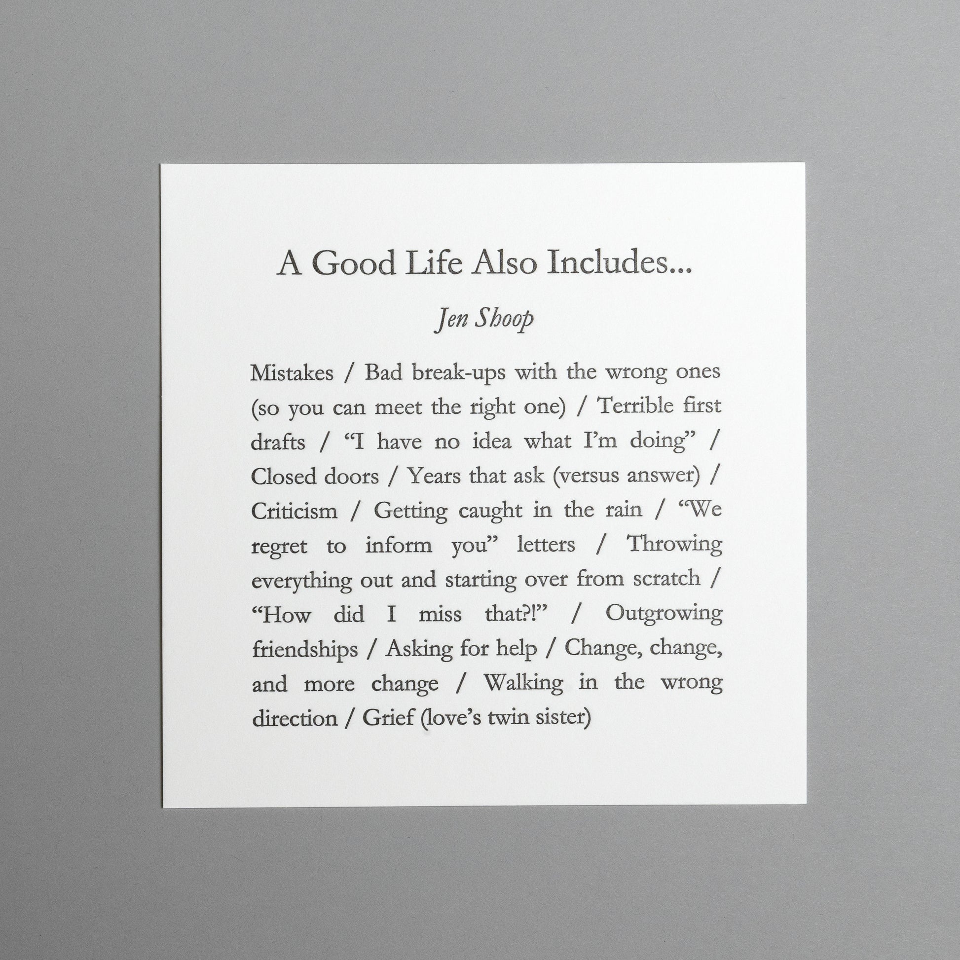 Front view of “A Good Life Also Includes…” 5×5 black letterpress print by Jen Shoop on white paper.