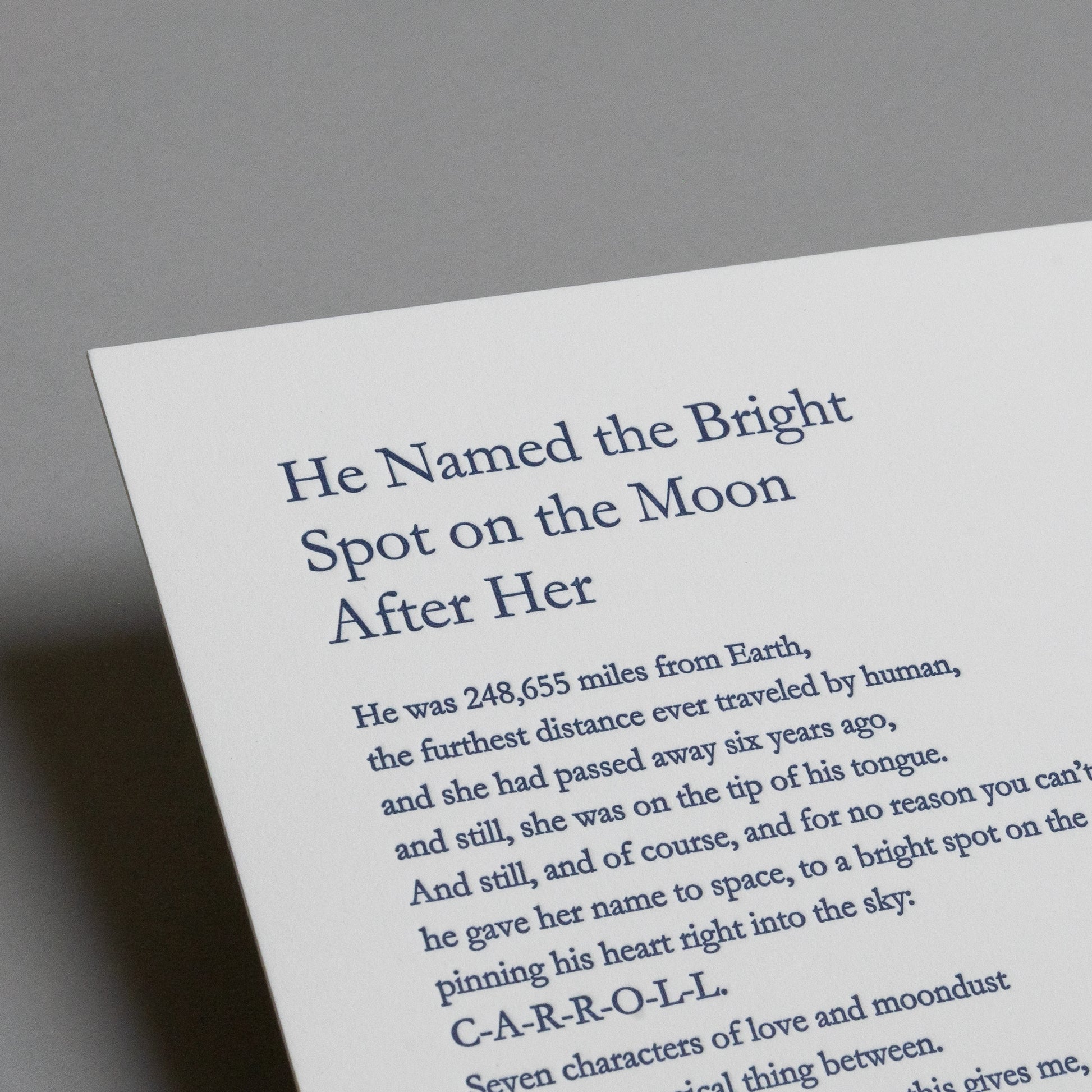 Close-up of the blue letterpress title and upper text on “He Named the Bright Spot on the Moon After Her.”