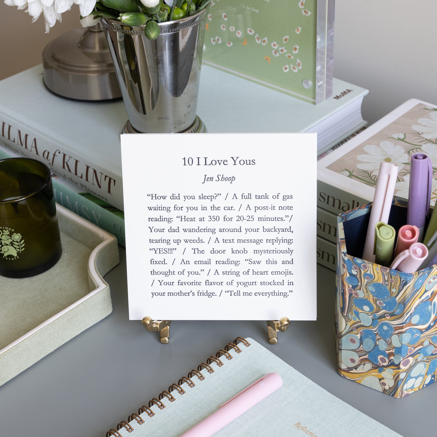 10 I Love Yous 5-by-5 poetry card by Jen Shoop displayed on a brass stand in a styled writing desk scene.