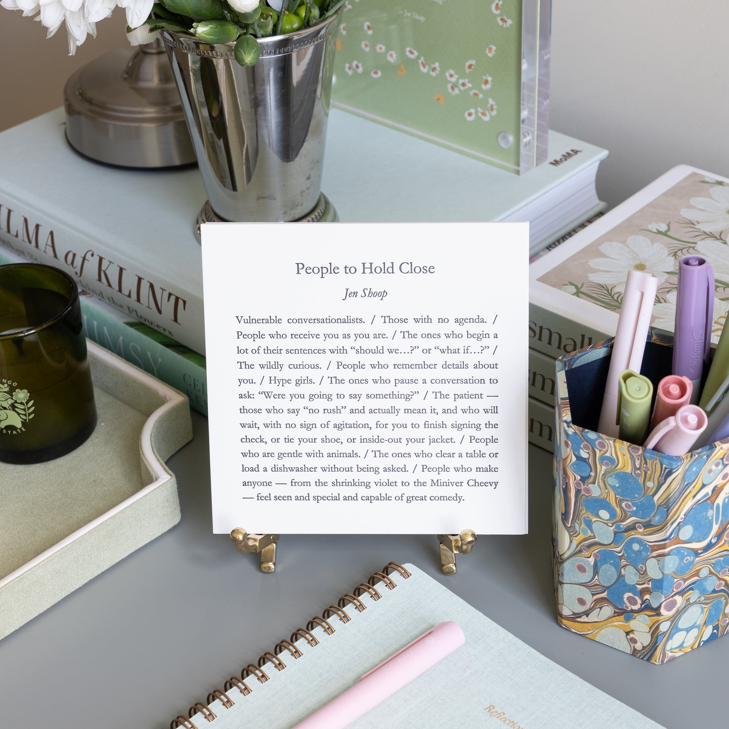 People to Hold Close 5-by-5 poetry card by Jen Shoop displayed on a brass stand in a styled writing desk scene.