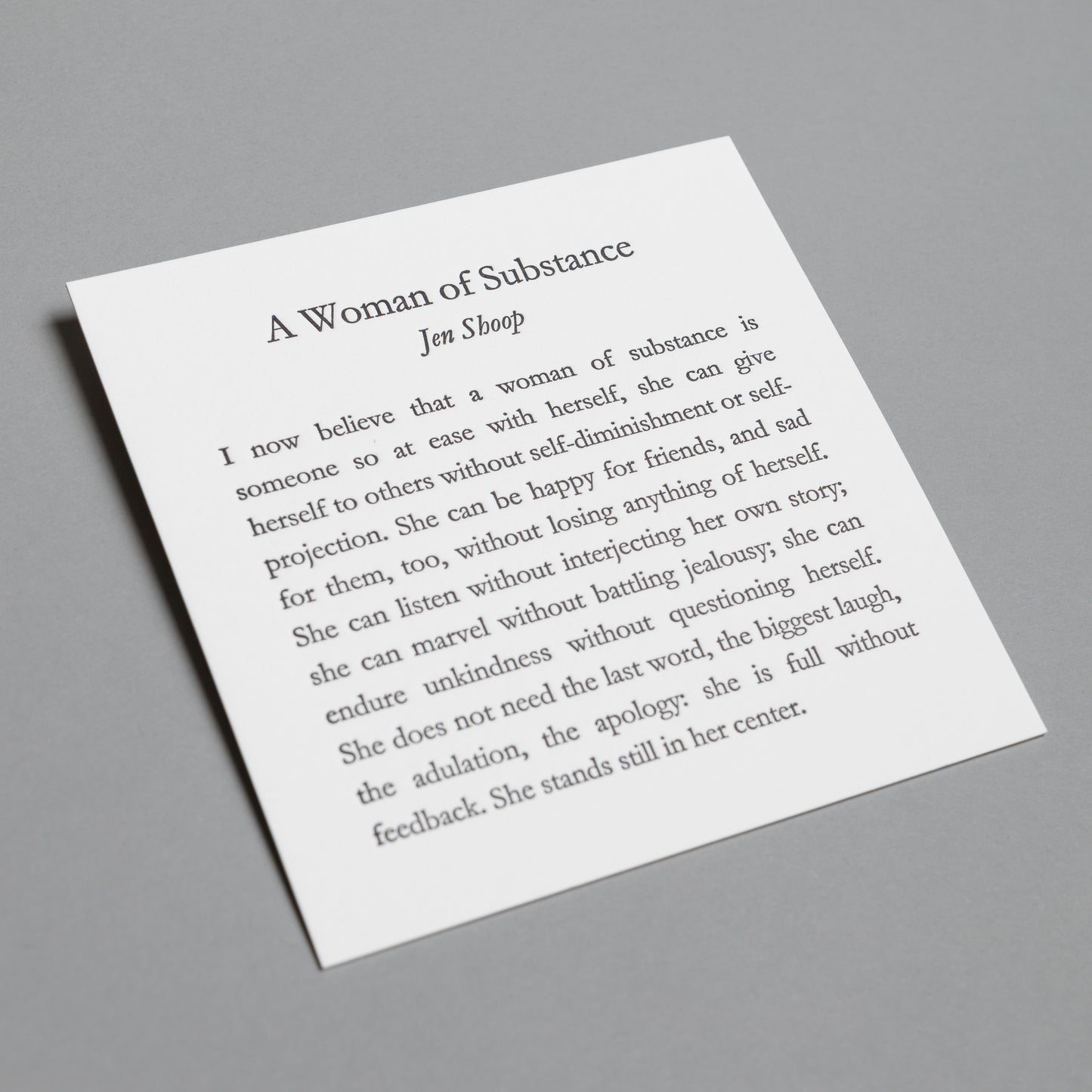 Angled view of “A Woman of Substance” 5×5 letterpress print, showing white paper and impressed type.