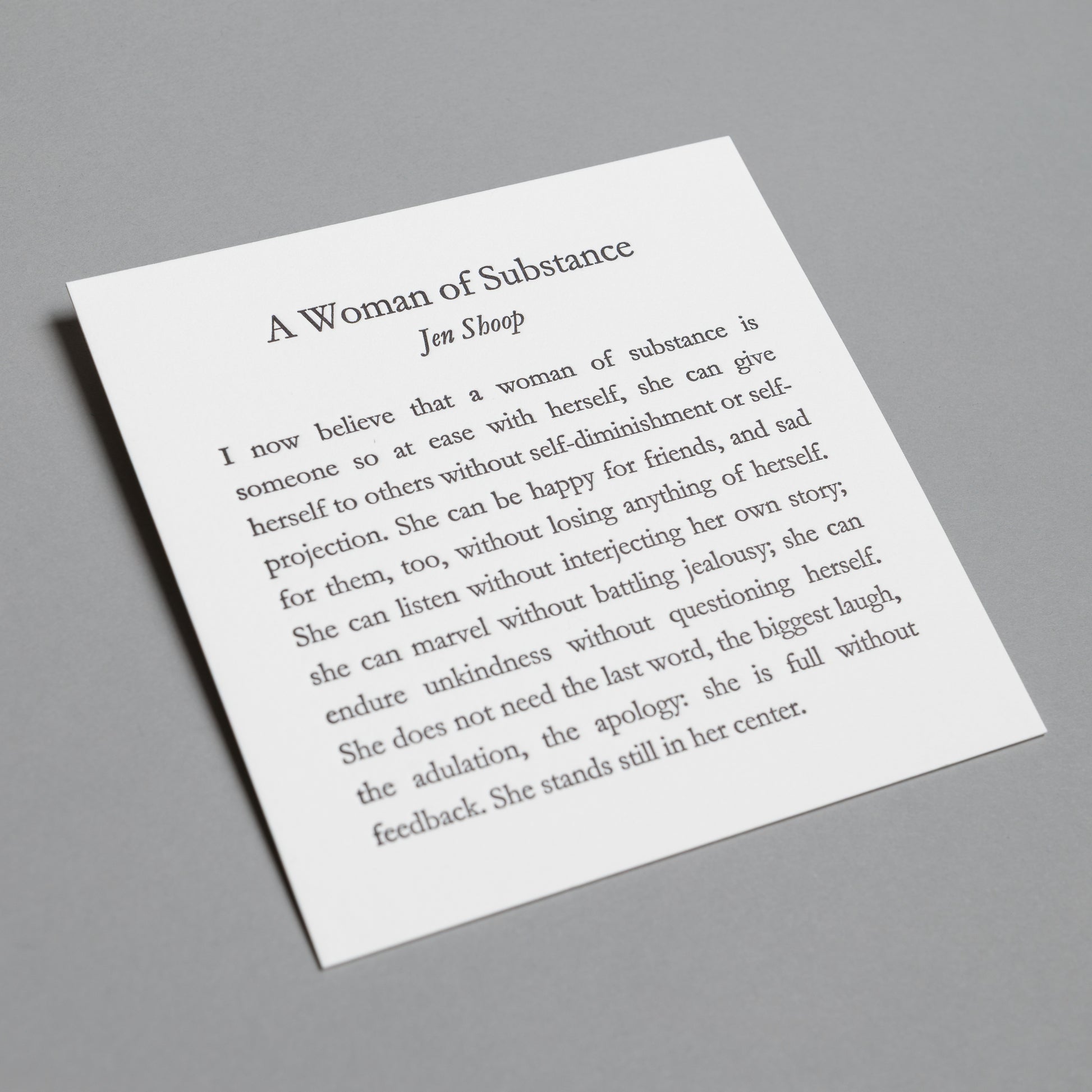 Angled view of “A Woman of Substance” 5×5 letterpress print, showing white paper and impressed type.